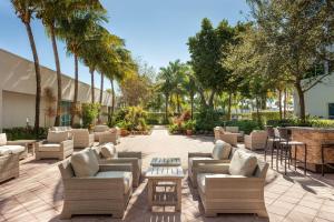 a patio with couches and tables and palm trees at West Palm Beach Marriott in West Palm Beach