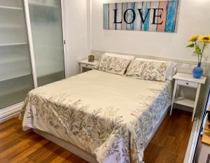 een kleine slaapkamer met een bed met een liefdesbord aan de muur bij LOFT vistas playa jardin in Puerto de la Cruz
