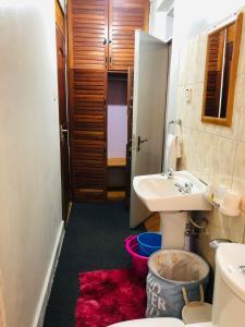 a bathroom with a sink and a toilet and a mirror at Cozy Pad in Kampala