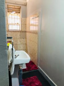 a bathroom with a sink and a toilet and a window at Cozy Pad in Kampala