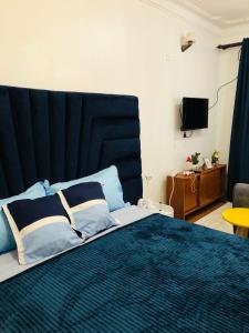 a bedroom with a large bed with a blue headboard at Cozy Pad in Kampala