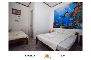 a room with two beds and a painting on the wall at Ocean Mist Tourist Inn in San Vicente