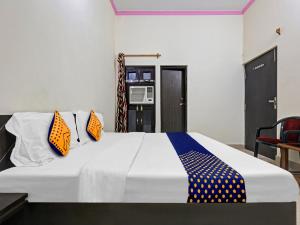 ein Schlafzimmer mit einem großen Bett mit orangefarbenen und blauen Kissen in der Unterkunft SPOT ON 81167 Hotel ASDR in Rudrapur