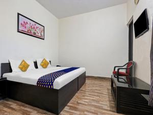 ein Schlafzimmer mit einem Bett und einem Stuhl in einem Zimmer in der Unterkunft SPOT ON 81167 Hotel ASDR in Rudrapur