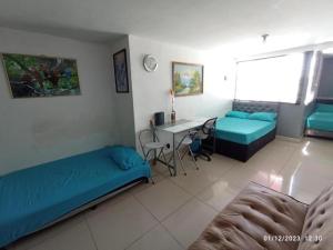 a room with two beds and a table and a desk at CENTRO! San Lorenzo - Downtown - Apartaestudio Familiar in Medellín