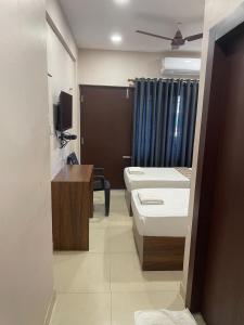 een badkamer met 2 bedden en een tv. bij Plaza Tourist Home in Kannur