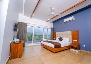 um quarto com uma cama e uma grande janela em Munnar Majestic Resorts by VOYE HOMES em Anachal