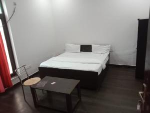 ein kleines Schlafzimmer mit einem Bett und einem Tisch in der Unterkunft Expo Mart in Greater Noida