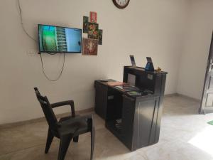 Zimmer mit einem Schreibtisch, einem TV und einem Stuhl in der Unterkunft Expo Mart in Greater Noida