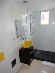 y baño con lavabo amarillo y ducha. en Monterosa Apartamentos Amoblados, en Pereira