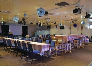 a banquet hall with tables and chairs and chandaliers at Pencnwc Holiday Park in Llanllwchaiarn