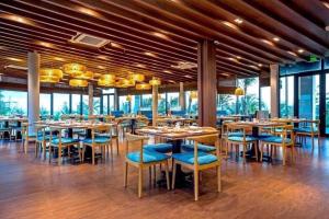 una sala da pranzo con tavoli, sedie e finestre di Khách Sạn - Resort Oceanami - Long Hải a Long Hai