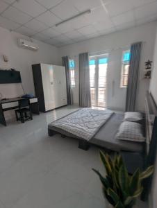 - une chambre avec un grand lit dans une pièce dotée de fenêtres dans l'établissement Mai Anh Garden 2, à Soc Trang