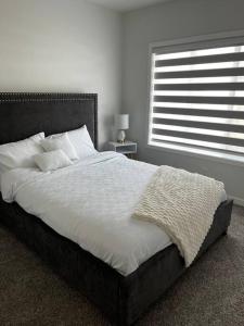 a bedroom with a large bed with a window at Brand New - Home Away from Home in NW Calgary in Calgary
