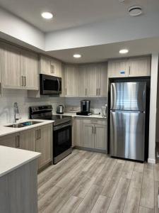 a kitchen with a stainless steel refrigerator and wooden cabinets at Brand New - Home Away from Home in NW Calgary in Calgary