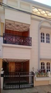 un gran edificio blanco con balcón y porche en Siddheshwara Home Stay, en Bangalore