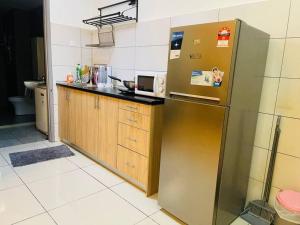 a kitchen with a stainless steel refrigerator and wooden cabinets at USJ One Residence Cozy Homestay Subang Jaya Sunway in Subang Jaya
