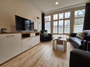 ein Wohnzimmer mit einem Sofa und einem Flachbild-TV in der Unterkunft Buten un Binnen in Norderney