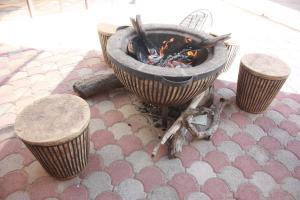 a fire pit on a floor with three stools at Apelles Palace Guest House in Gaborone