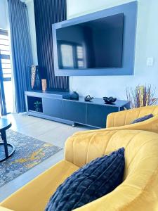 a living room with a yellow couch and a large tv at Get Cosy & Comfy kaZwide villa in Nelspruit
