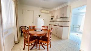 a kitchen with a table and chairs and a refrigerator at Motel Myall in Dalby