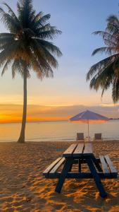 a picnic table on a beach with a palm tree at Two Bedroom Apartment at The Nove Nuvasa Bay Nongsa 306 in Nongsa
