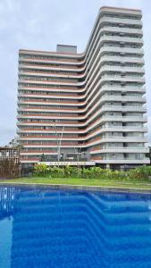 a large building with a large swimming pool in front of it at Two Bedroom Apartment at The Nove Nuvasa Bay Nongsa 306 in Nongsa