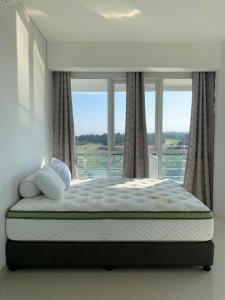 a bed in a room with a large window at Two Bedroom Apartment at The Nove Nuvasa Bay Nongsa 306 in Nongsa