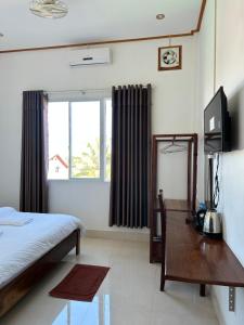 a bedroom with a bed and a desk and a television at narixay hotel in Phonsavan