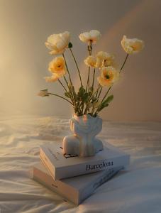un jarrón de flores sentado encima de un libro en 홍대 입구역 7min, Designer house, 대형빔, 2R, 포토존, 신축, 최대5인 en Seúl