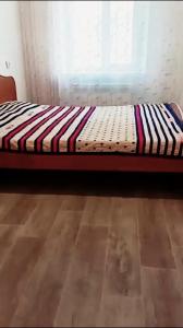 Bett in einem Zimmer mit Fenster in der Unterkunft 3-х комнатная квартира в Павлодаре in Pawlodar