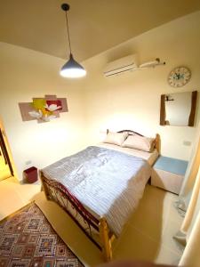 Furnished Chalet Apartment at La Hacienda Ras Sedr في رأس سدر: غرفة نوم بسرير وساعة على الحائط