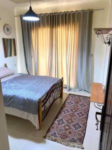a bedroom with a bed and a window with curtains at Furnished Chalet Apartment at La Hacienda Ras Sedr in Ras Sedr