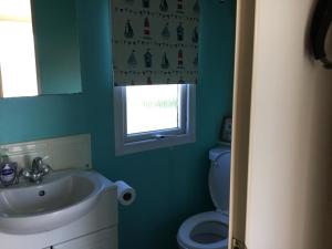 a bathroom with a sink and a toilet and a window at Mersea Island at Lazeeedays in Colchester +30 photos