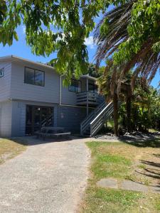a house with a palm tree in front of it at Beach House Matauri Bay in Matauri Bay