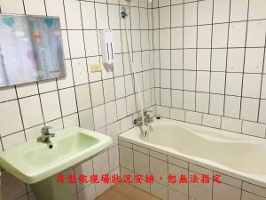 een wit betegelde badkamer met een wastafel en een bad bij Gui Zu Hotel in Luodong