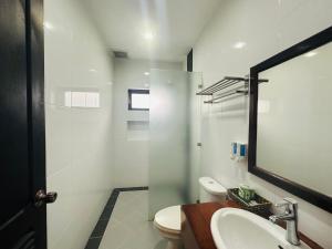 a bathroom with a toilet and a sink and a mirror at Villa Ban Pakham Hotel in Luang Prabang