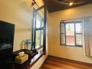 a room with two windows and a wooden table at Villa Ban Pakham Hotel in Luang Prabang
