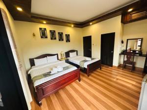 een slaapkamer met 2 bedden en een houten vloer bij Villa Ban Pakham Hotel in Luang Prabang