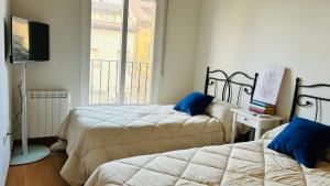 - une chambre avec 2 lits, une télévision et une fenêtre dans l'établissement El Pajar del Toro, à San Cristóbal de Segovia