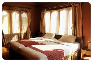 two beds sitting in a room with windows at Hotel Jigmeling in Paro
