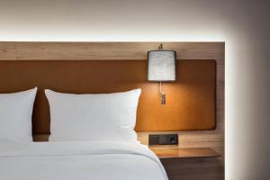 a bedroom with a white bed with a lamp on it at MOXY Berlin Humboldthain Park in Berlin