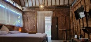 a bedroom with a bed and a television in a room at Villas Light House - Eco-Traditional Joglo in Gili Trawangan