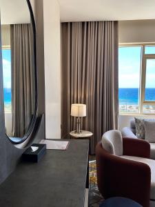 a living room with a mirror and a room with the ocean at Enala Hotel- Umluj in Umm Lujj