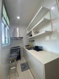 a white kitchen with a counter and a stove at MyHome Batu Feringghi Penang in Batu Ferringhi