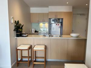 a kitchen with a counter with two stools and a refrigerator at Hobart Inner City Apartment in Hobart
