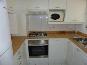 cocina con armarios blancos y fogones en Apartmento San Alfonso Vista Mar, en Algarrobo