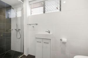 a white bathroom with a sink and a shower at Island View Unit 3, 23 Esplanade, Bulcock Beach in Caloundra