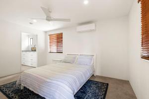 a white bedroom with a bed and a ceiling fan at Island View Unit 3, 23 Esplanade, Bulcock Beach in Caloundra