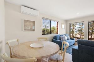 a living room with a table and a blue couch at Island View Unit 3, 23 Esplanade, Bulcock Beach in Caloundra